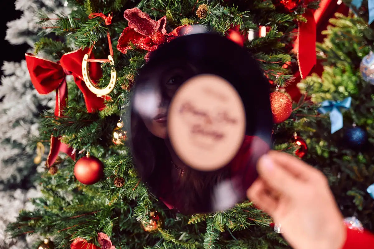 A black vinyl record with a printed face on its surface, held in front of a decorated christmas tree.