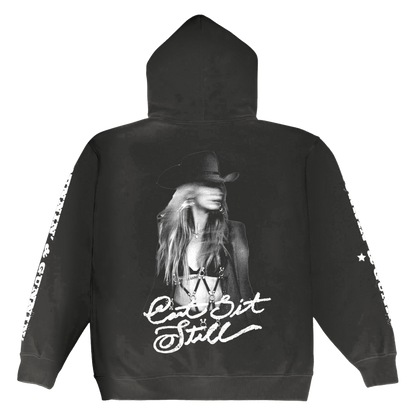 Black hoodie featuring a black-and-white graphic of a woman in a cowboy hat with the text ’can’t sit still’ printed below.