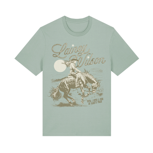 A light mint green short-sleeved t-shirt featuring a vintage-style graphic of a rider on horseback under a full moon, with the name ’laney wilson’ scripted above in an ornate font.