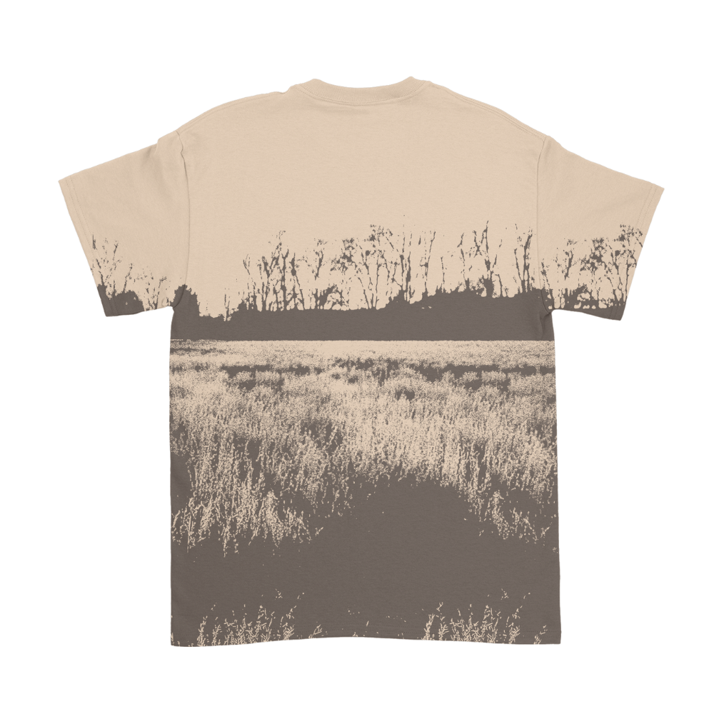 Beige t-shirt featuring a sepia-toned print of a field with tall grass and bare trees in the distance.