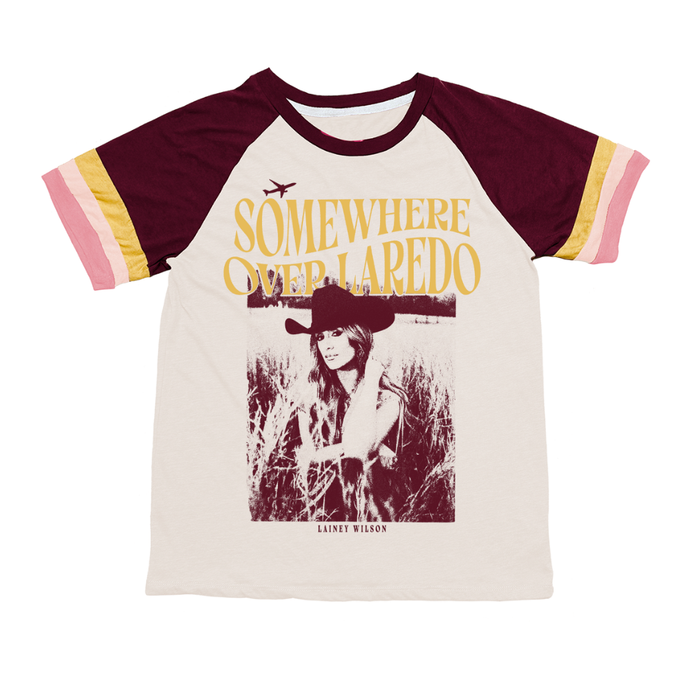 Cream-colored raglan t-shirt with maroon sleeves and striped cuffs, featuring a vintage-style graphic of lainey wilson in a cowboy hat beneath the text ’somewhere over laredo.’