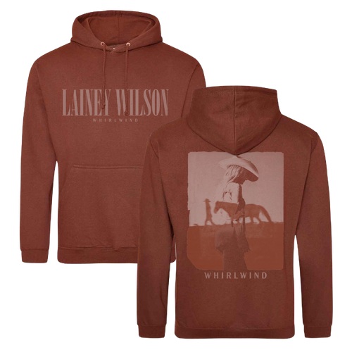 Rust-colored hoodie featuring ’lainey wilson’ and ’whirlwind’ branding with a graphic of a figure in a hat walking beside a horse on the back.