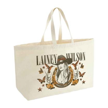 Cream-colored canvas tote bag featuring a printed design of lainey wilson in a hat, surrounded by butterflies and stars.