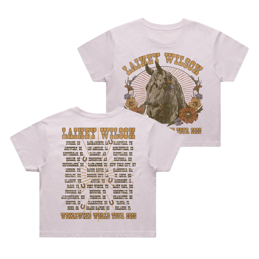 White cropped t-shirt featuring a detailed illustration of a horse surrounded by flowers on the front and an extensive tour itinerary printed across the back.